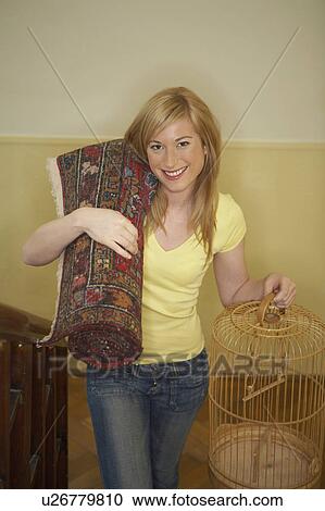 Young woman carrying empty birdcage and rug, smiling, portrait View Large Photo Image Stock Image - Young woman carrying empty birdcage and rug, smiling, portrait. Fotosearch