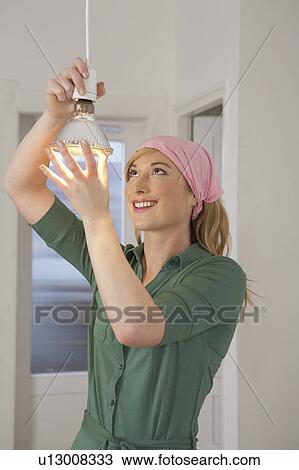 Young woman changing light bulb, smiling View Large Photo Image Stock Image - Young woman changing light bulb, smiling. Fotosearch