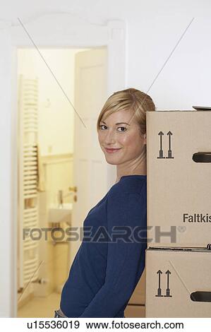 Young woman leaning against packing cases smiling, portrait View Large Photo Image Stock Photo - Young woman leaning against packing cases smiling, portrait. Fotosearch