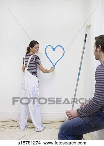 Young woman painting heart on wall View Large Photo Image Picture - Young woman painting heart on wall . Fotosearch