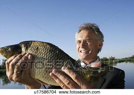 Businessman holding a fish. View Large Photo Image Picture - Businessman holding a fish.. Fotosearch