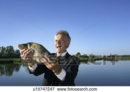 Stock Photo - Businessman holding a fish.. Fotosearch