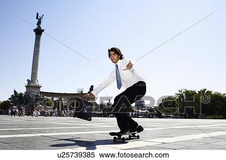 Stock Photography - Businessman on skateboard in Hero Square.. Fotosearch