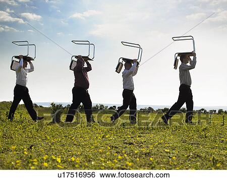 Stock Photograph - Businessmen walking through field with chairs.. Fotosearch