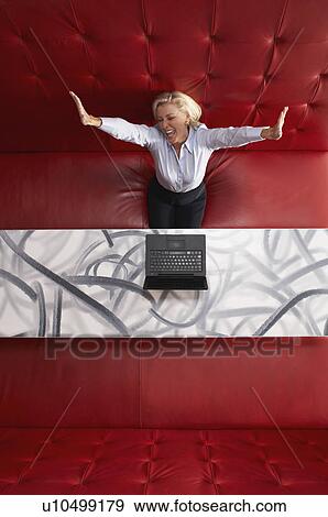 Stock Photo - Businesswoman working at a table with red seating. Fotosearch