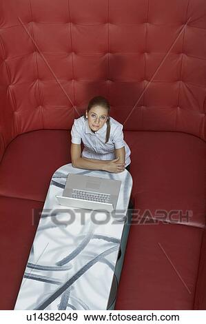 Stock Photo - Businesswoman working at a table with red seating. Fotosearch