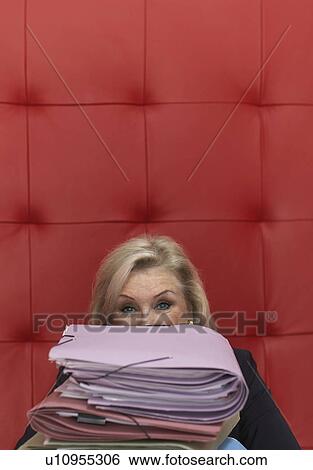 Stock Photograph - Businesswoman working at a table with red seating. Fotosearch