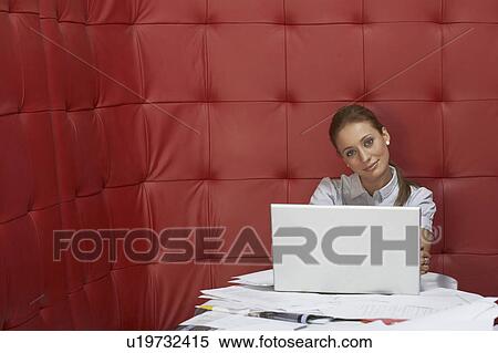Businesswoman working at a table with red seating View Large Photo Image Stock Photography - Businesswoman working at a table with red seating. Fotosearch