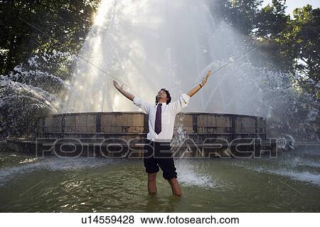 Stock Photo - Excited businessman standing in fountain.. Fotosearch