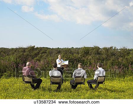 Picture - Group of businesspeople sitting on chairs in field.. Fotosearch