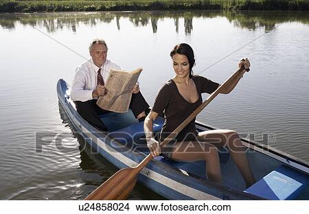 Picture - Young woman and businessman in canoe.. Fotosearch