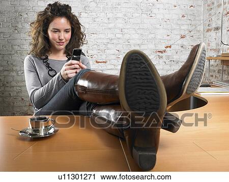 Businesswoman reading text message, feet up on desk., Brussels, Belgium. View Large Photo Image Stock Image - Businesswoman reading text message, feet up on desk., Brussels, Belgium.. Fotosearch