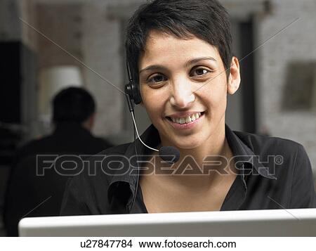 Picture - Businesswoman wearing headset, working on laptop. Brussels, Belgium.. Fotosearch