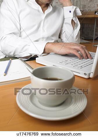 Stock Photo - Close-up of coffee cup with businessman in background., Brussels, Belgium.. Fotosearch