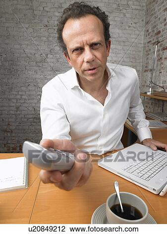 Stock Image - Concerned businessman giving a phone to camera., Brussels, Belgium.. Fotosearch