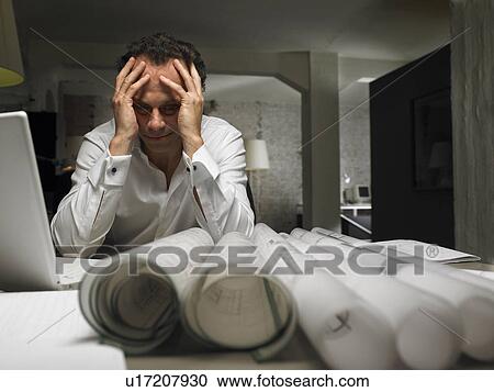 Male architect sitting at desk with head in hands, night View Large Photo Image Stock Image - Male architect sitting at desk with head in hands, night. Fotosearch