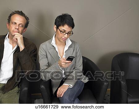 Mature man looking at woman's mobile phone in waiting room View Large Photo Image Stock Photo - Mature man looking at woman's mobile phone in waiting room. Fotosearch