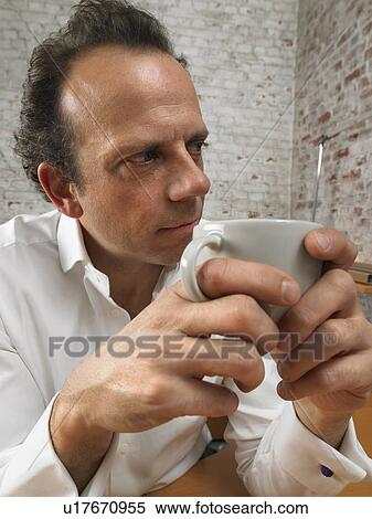 Stock Photography - Pensive businessman holding coffee cup., Brussels, Belgium.. Fotosearch