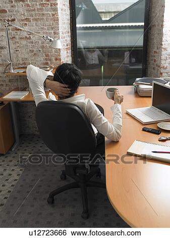 Rear view of businesswoman having coffee at her desk at dusk. Brussels, Belgium. View Large Photo Image Stock Photograph - Rear view of businesswoman having coffee at her desk at dusk. Brussels, Belgium.. Fotosearch