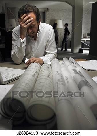 Stressed architect at desk, two females in background. Brussels, Belgium. View Large Photo Image Stock Photo - Stressed architect at desk, two females in background. Brussels, Belgium.. Fotosearch