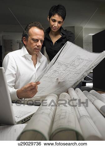 Stock Photograph - Two architects reading a blueprint. Brussels, Belgium.. Fotosearch