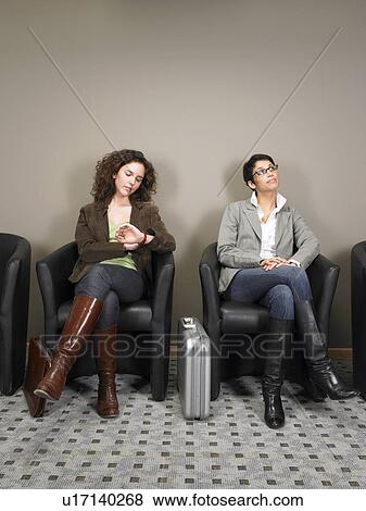 Stock Photo - Two businesswomen sitting in waiting room. Brussels, Belgium.. Fotosearch