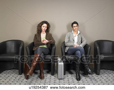 Stock Photo - Two businesswomen sitting in waiting room. Brussels, Belgium.. Fotosearch
