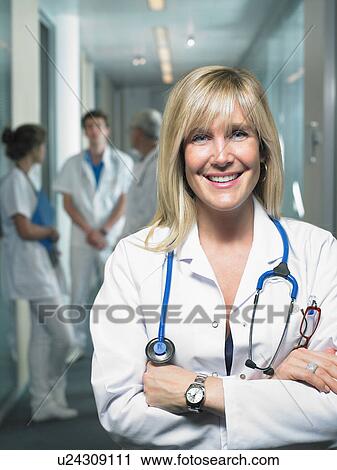 Group of four doctors in a lobby of a hospital. Female doctor in foreground. Smiling. View Large Photo Image Stock Image - Group of four doctors in a lobby of a hospital. Female doctor in foreground. Smiling.. Fotosearch