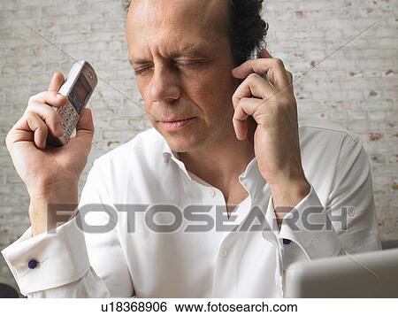 Mature businessman using two mobile phones, eyes closed View Large Photo Image Stock Photograph - Mature businessman using two mobile phones, eyes closed. Fotosearch