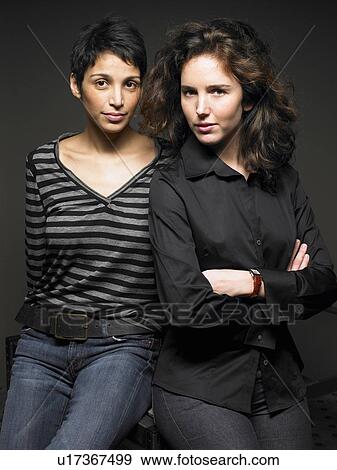Two women sitting side by side on desk, portrait View Large Photo Image Stock Photo - Two women sitting side by side on desk, portrait. Fotosearch
