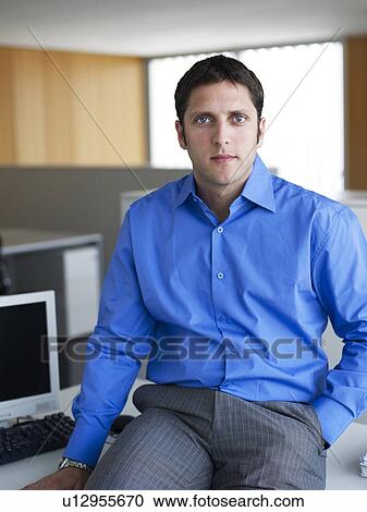 Young businessman sitting on desk in office, portrait View Large Photo Image Stock Image - Young businessman sitting on desk in office, portrait. Fotosearch