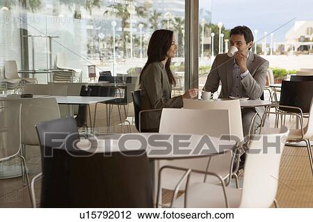 Stock Image - Businessman and businesswoman sitting outside café drinking coffee. Alicante, Spain.. Fotosearch