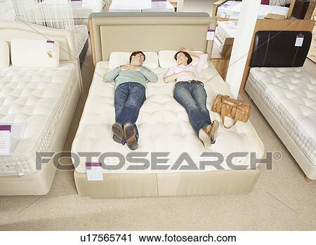 Couple lying on bed in furniture store. View Large Photo Image Stock Image - Couple lying on bed in furniture store.. Fotosearch