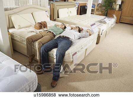 Couple lying on bed in furniture store. View Large Photo Image Stock Photo - Couple lying on bed in furniture store.. Fotosearch