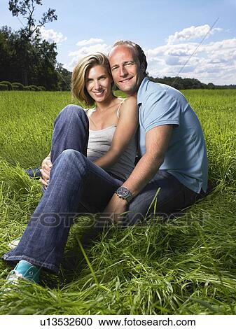 Couple sitting in a field. View Large Photo Image Stock Image - Couple sitting in a field.. Fotosearch