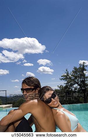 Couple sunbathing by a swimming pool View Large Photo Image Stock Image - Couple sunbathing by a swimming pool. Fotosearch