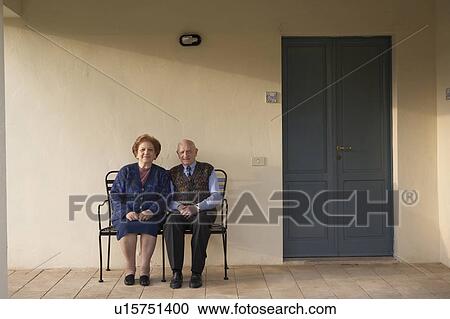 Stock Image - Senior couple on bench outdoors, portrait. Fotosearch