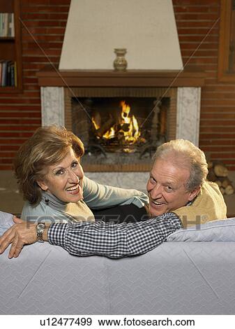 Senior couple relaxing in living room, smiling, portrait View Large Photo Image Stock Photo - Senior couple relaxing in living room, smiling, portrait. Fotosearch