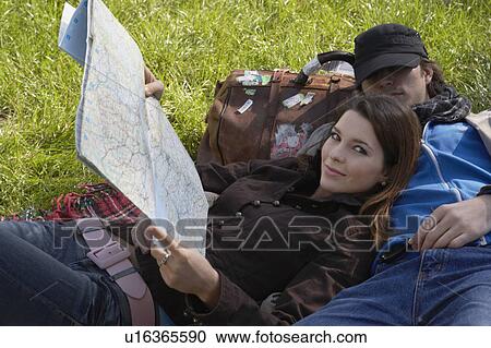Woman smiling holding map reclining on sleeping man in a park. View Large Photo Image Stock Image - Woman smiling holding map reclining on sleeping man in a park.. Fotosearch