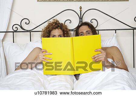 young couple in bed holding yellow book, portrait View Large Photo Image Stock Image - young couple in bed holding yellow book, portrait. Fotosearch