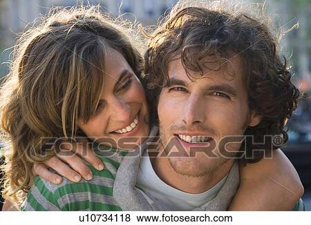 Stock Photo - Young couple outdoors, heads together, smiling, close-up. Fotosearch