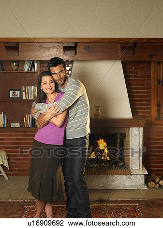 Young couple standing in living room, smiling, portrait View Large Photo Image Stock Image - Young couple standing in living room, smiling, portrait. Fotosearch