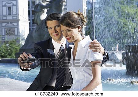 Stock Photo - Young couple taking picture together beside fountain.. Fotosearch