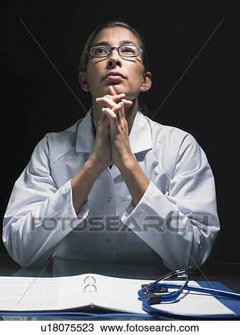 Close-up of female doctor thinking at her desk. View Large Photo Image Stock Image - Close-up of female doctor thinking at her desk.. Fotosearch