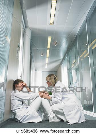 Concerned female doctor being reassured by another doctor in hospital lobby. View Large Photo Image Stock Photograph - Concerned female doctor being reassured by another doctor in hospital lobby.. Fotosearch
