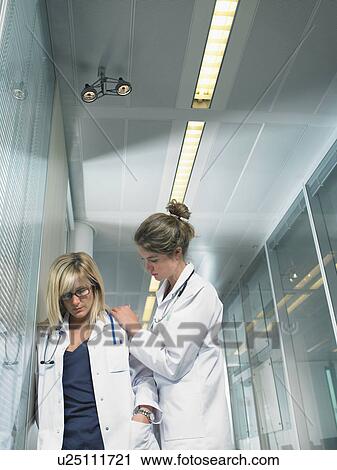 Female doctor being reassured by young female doctor in a lobby of a hospital. View Large Photo Image Stock Image - Female doctor being reassured by young female doctor in a lobby of a hospital.. Fotosearch