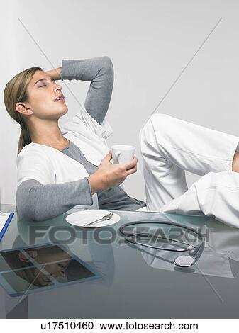Female doctor relaxing at her desk. View Large Photo Image Stock Image - Female doctor relaxing at her desk.. Fotosearch