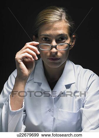 Stock Photo - Female doctor sitting at desk working late.. Fotosearch