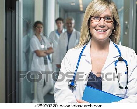 Group of four doctors in a lobby of a hospital. Female doctor in foreground. Smiling. View Large Photo Image Stock Image - Group of four doctors in a lobby of a hospital. Female doctor in foreground. Smiling.. Fotosearch