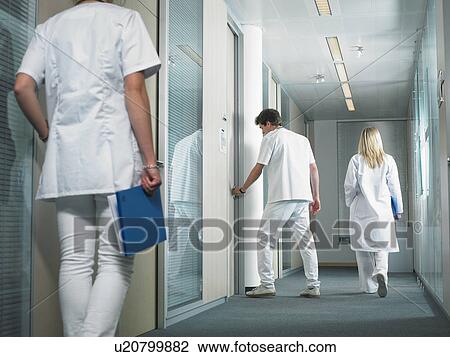 Male doctor opening door in a lobby of a hospital. Two female doctors walking in the lobby. View Large Photo Image Stock Image - Male doctor opening door in a lobby of a hospital. Two female doctors walking in the lobby.. Fotosearch